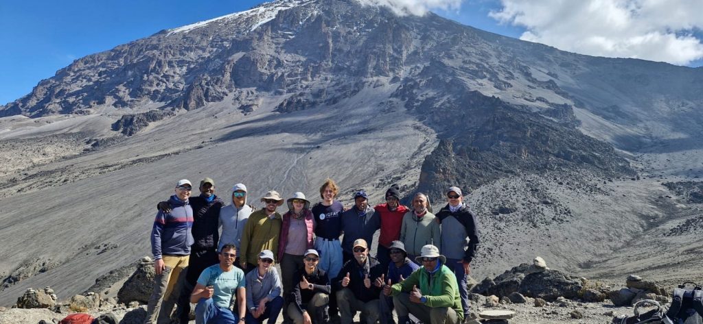 Large trekking group photographed below grey scree slopes on Mount Kilimanjaro