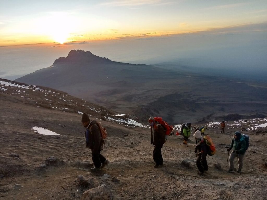 Porters and trekkers climbing a steep scree slope at sunrise, the character of the Umbwe Route