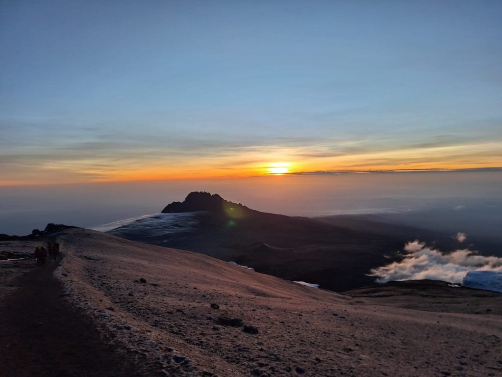 Sunrise over a jagged peak seen from the summit ridge of Mount Kilimanjaro