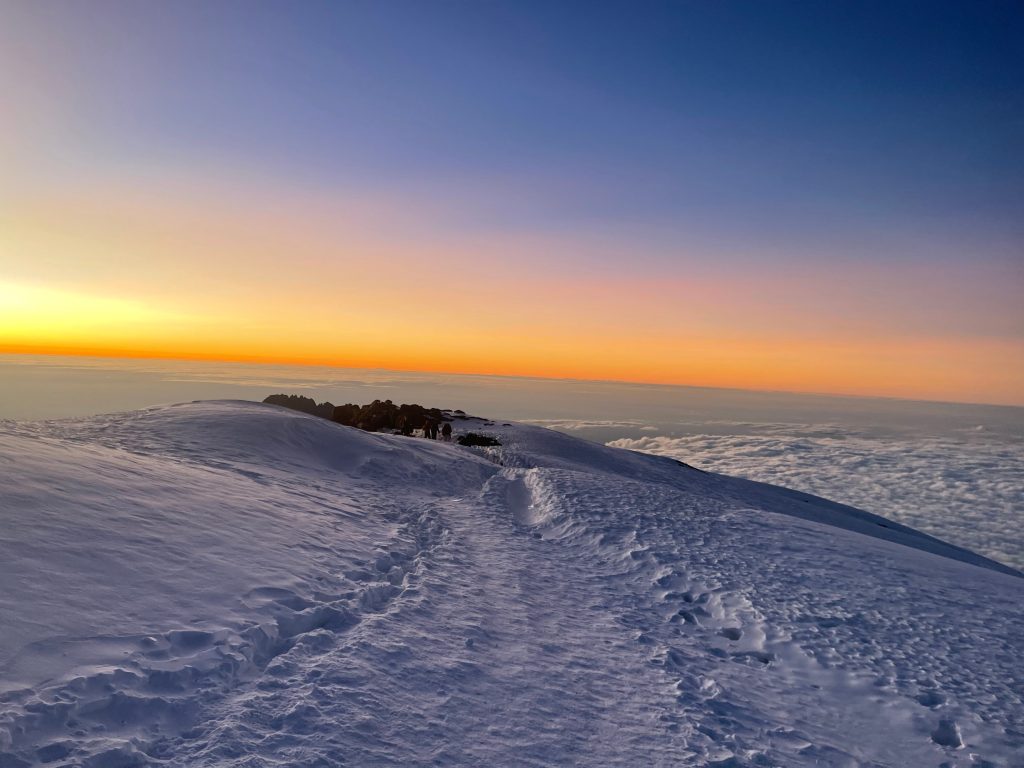 Trail running along the snowy crater rim of Kibo at sunrise on Mount Kilimanjaro