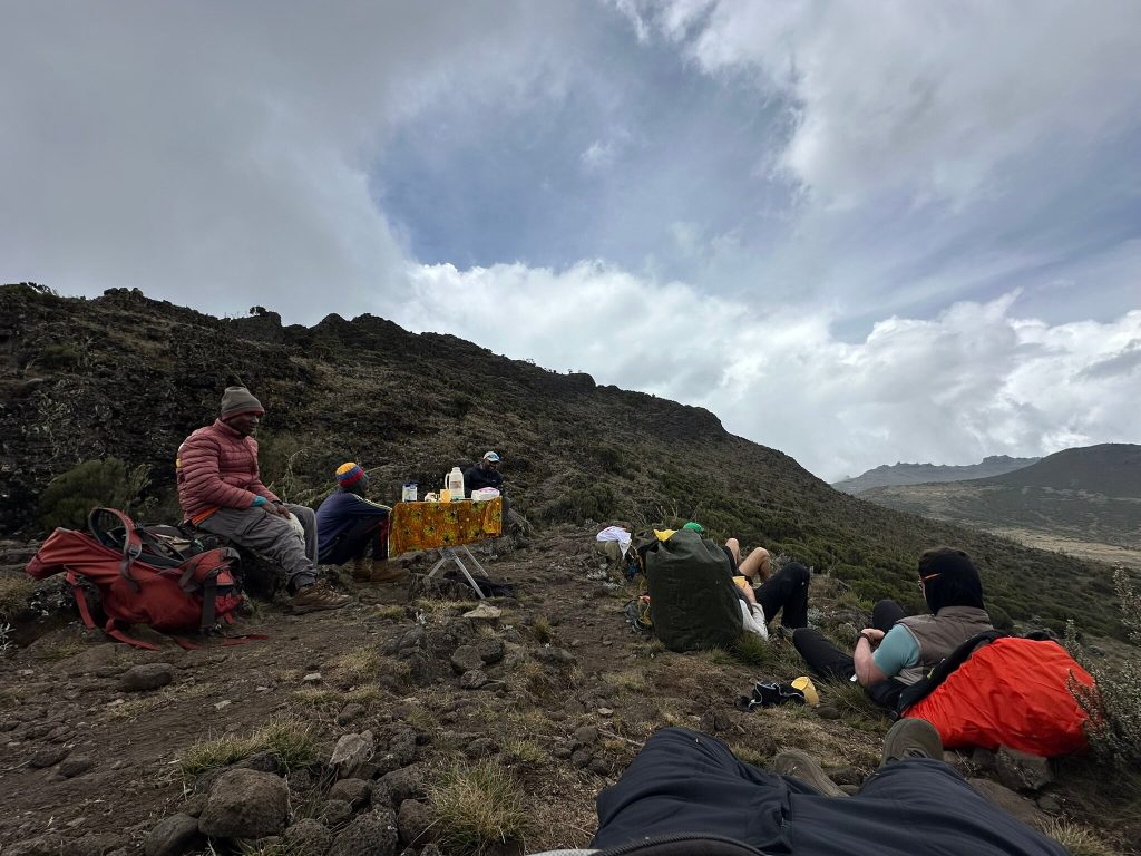 Trekkers resting at snack table on ridge on Mount Kilimanjaro