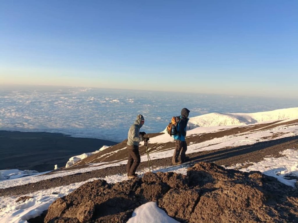 Two trekkers above cloud sea at sunrise on Mount Kilimanjaro